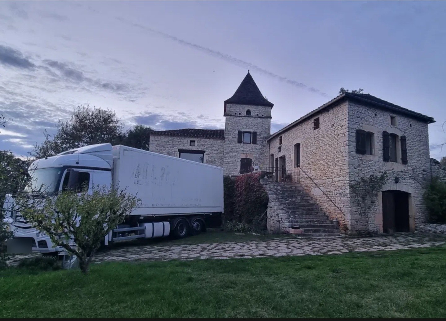 Camion Rivage Transport devant une bastide en pierre au crépuscule